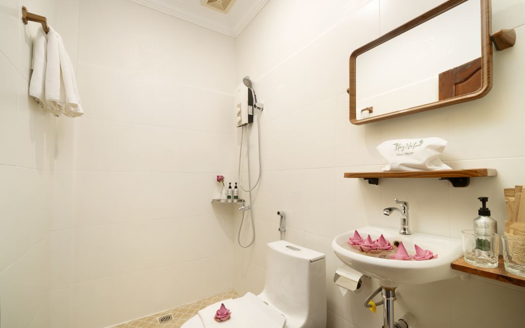 Bathroom at the Tree Hotel with shower, toilet, sink, mirror, and flower decorations.